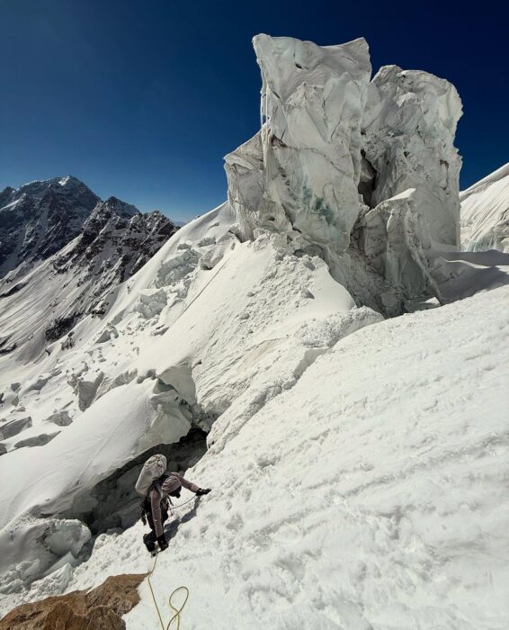 A climber on an ice slope, with a towering serac by his side. 