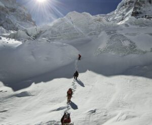 Sherpas in line on a snow slope with the serac in front of them.