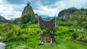 A black-roofed structure in the jungle, mountains in the distance