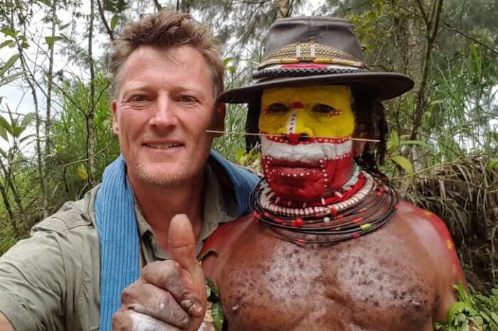 British adventurer Benedect Allen posing for a photo with a Papuan tribesman