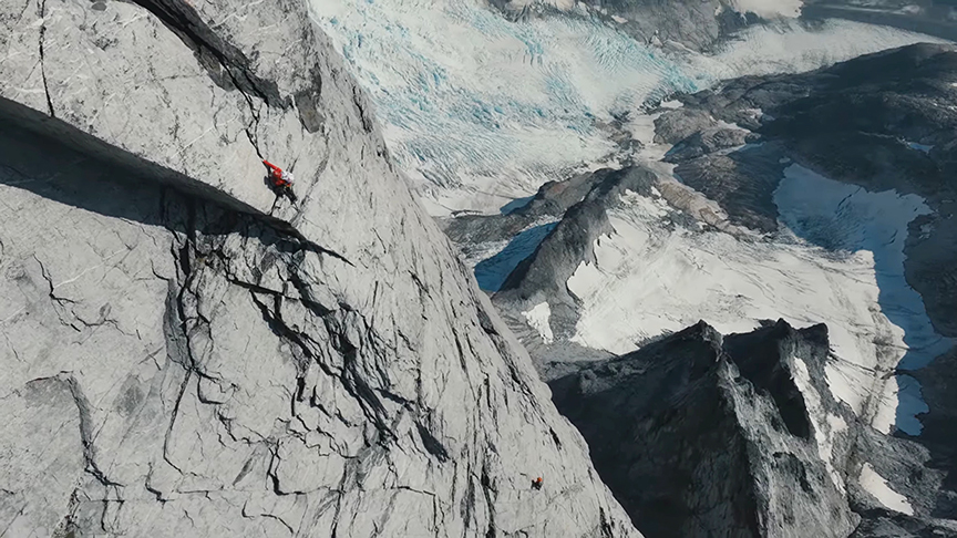 Two small figures climbing a grey cliff