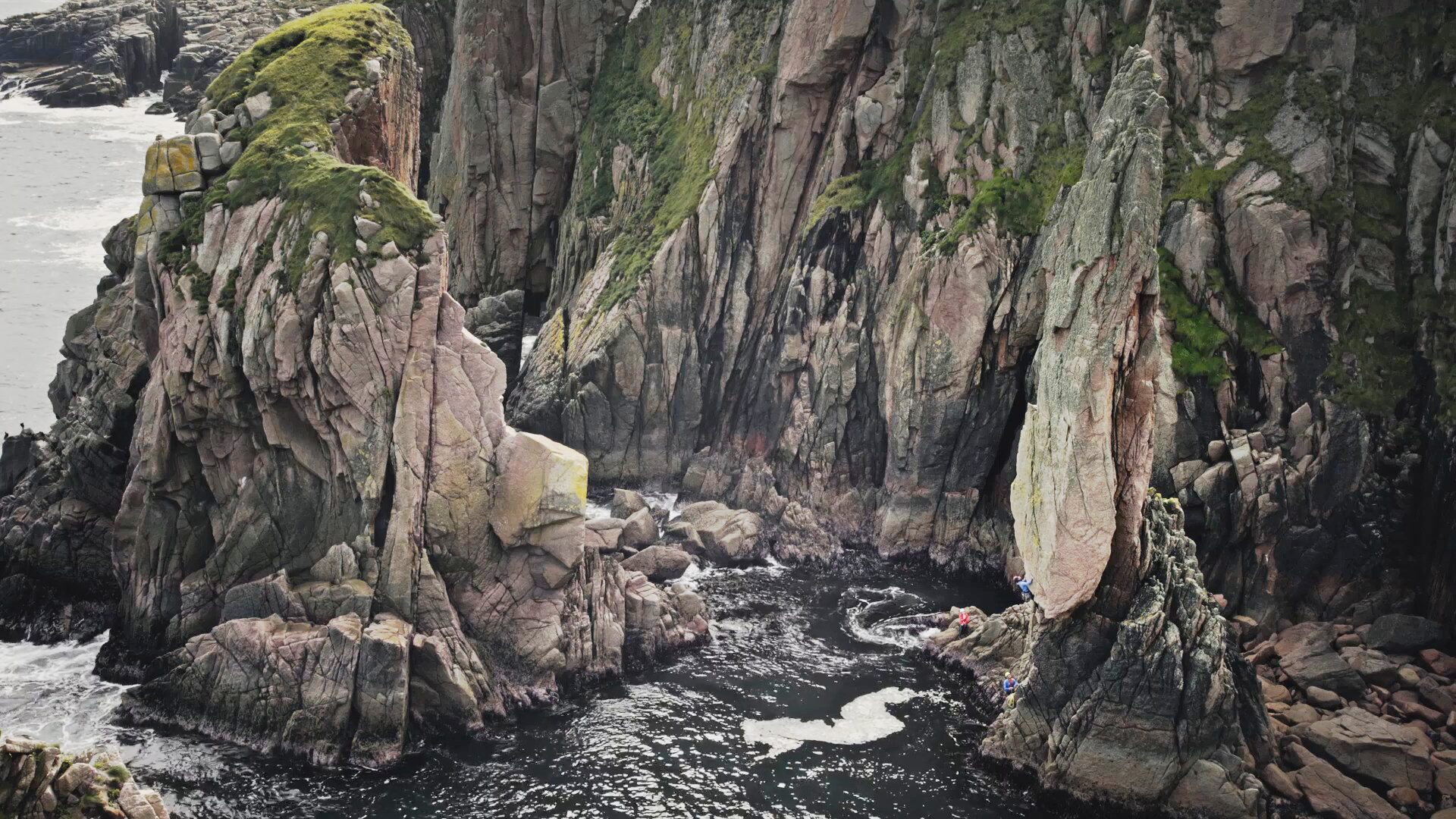 Granite sea cliffs and tiny figures climbing them