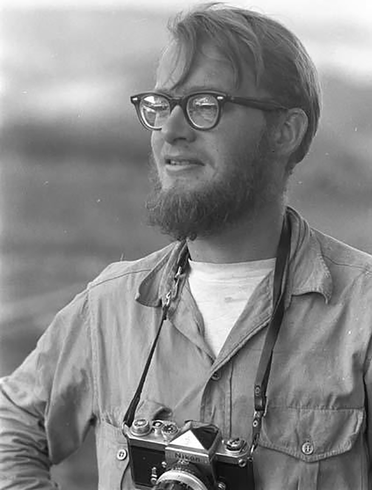 portrait of bespeckled man with camera around neck