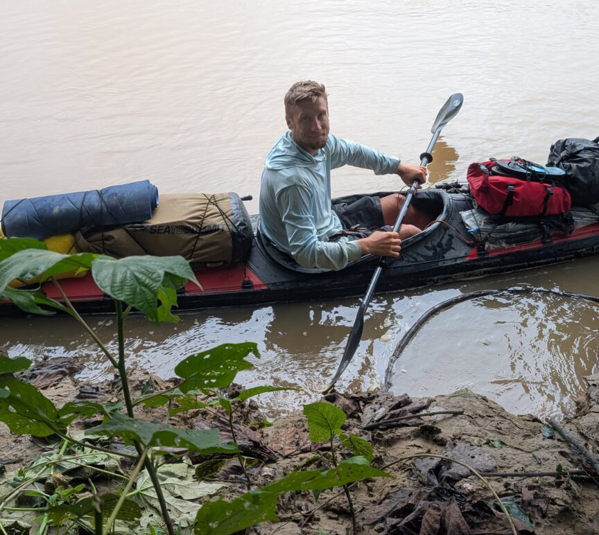 man in kayak by river shoreline