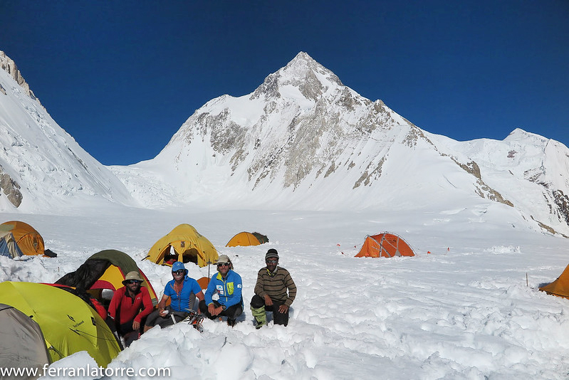 Some tents at CI on the gasherbrums in a sunny days, with some climbers sitting in the sun.