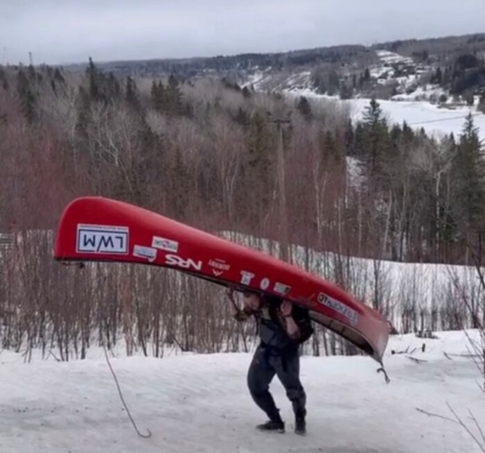 Adventurer carries canoe on shoulders on a long portage