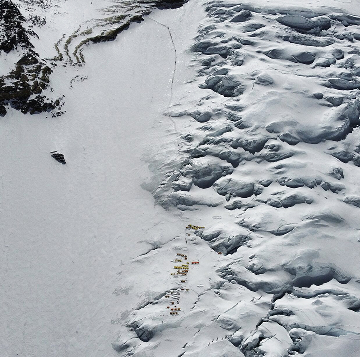 Aerial shot of the Lhotse face with the tents of Camp 3 and a black line of climbers marching toward thge summit of Everest.