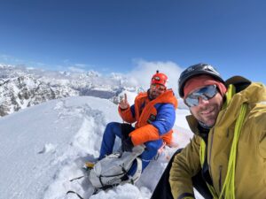 wo climbers sitting on a snowy summit.
