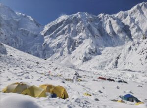 Some tents at the foot of a snowy Nanga Parbat, in a sunny day.