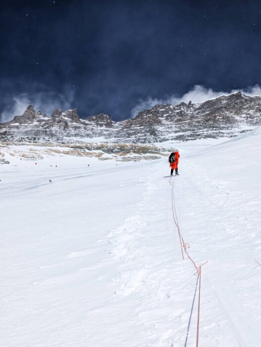 a climber on a snow slope, on fixed ropes, Lhotse summit area above him.