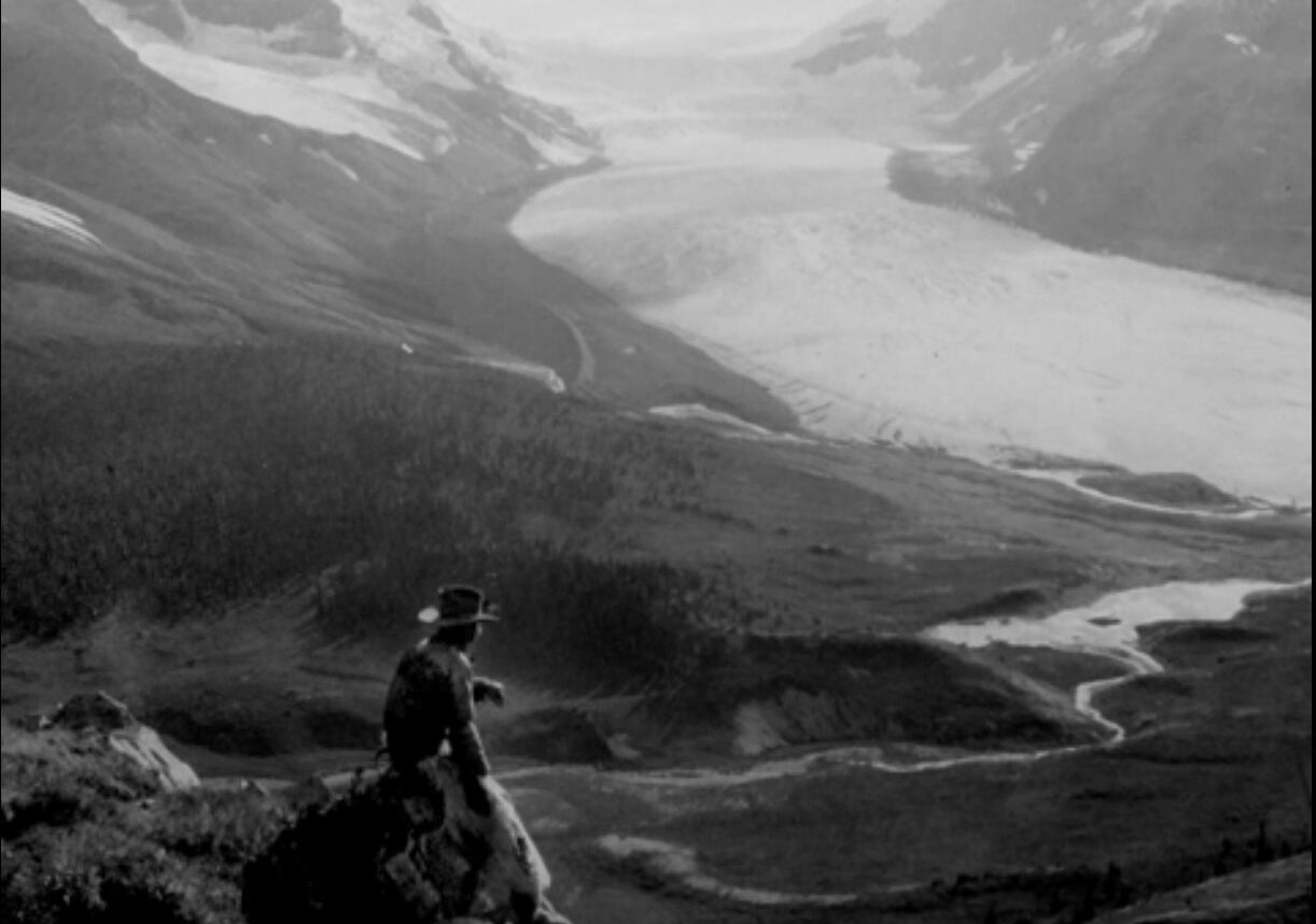 overview of mountain, glacier and person for scale in old black and white photo