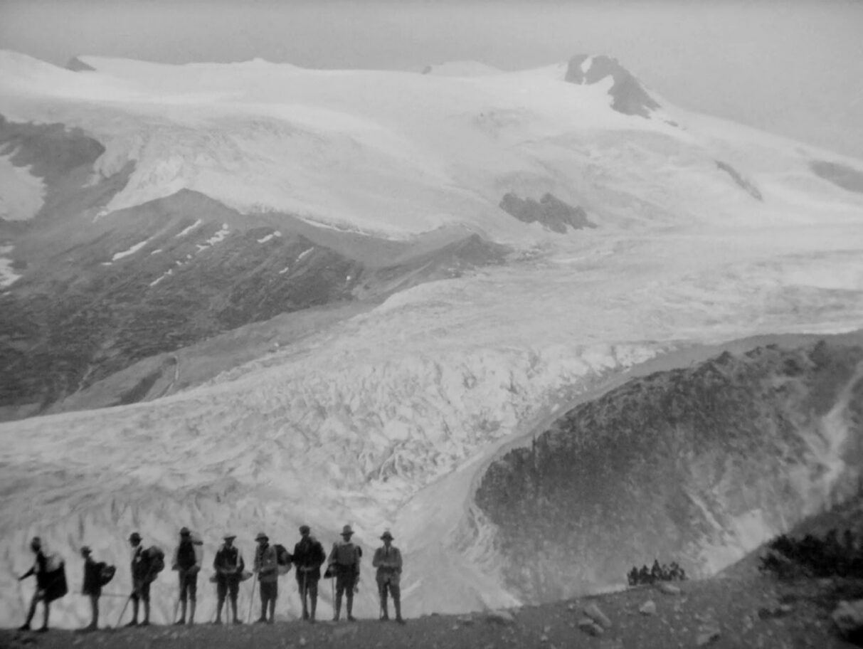 A group of men silhouetted against the mountains.