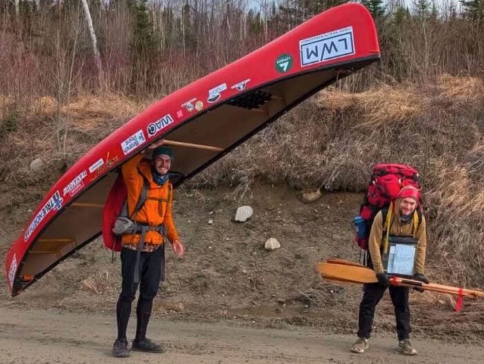 Adventurer carries canoe on shoulders on a long portage