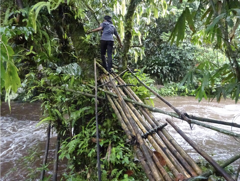 hiker crossing rickety bamboo bridge