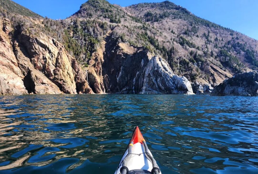 tip of kayak looking toward shoreline rocks