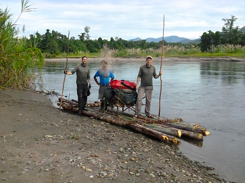 three men standing by log raft