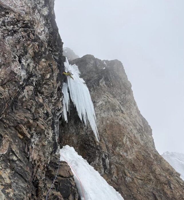 A climber on a hanging bunch of icicles.