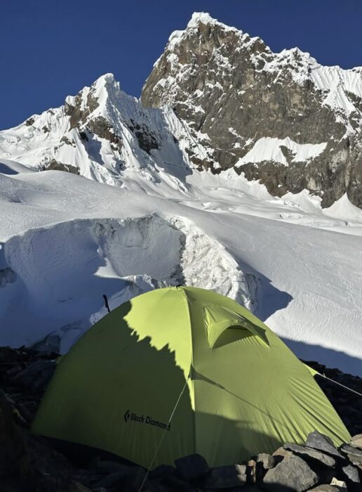 A tent at the foot of a mixed Andean mountain.