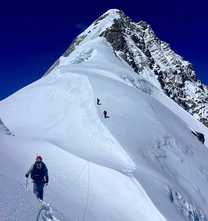Climbers on a snowy ridge to an Himalayan summit.