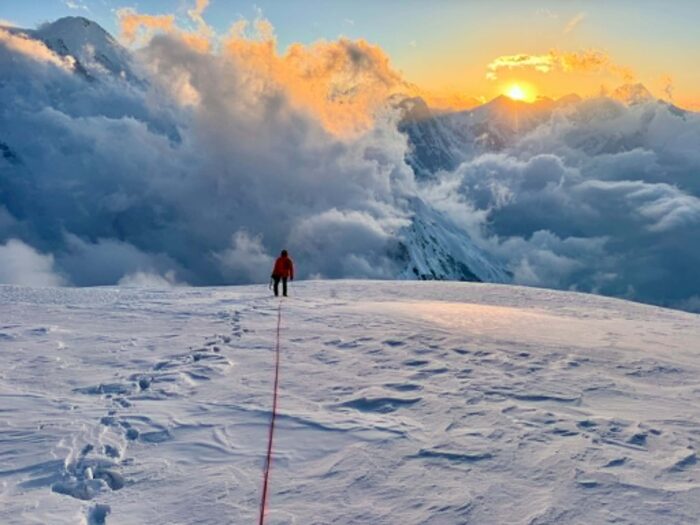 A climber on a snow plateau at dawn. 