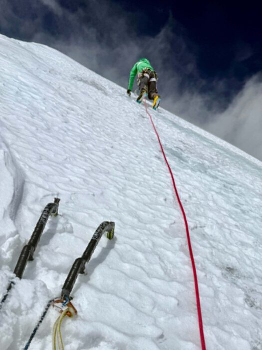 A climber up a steep ice ramp as seen from below. 
