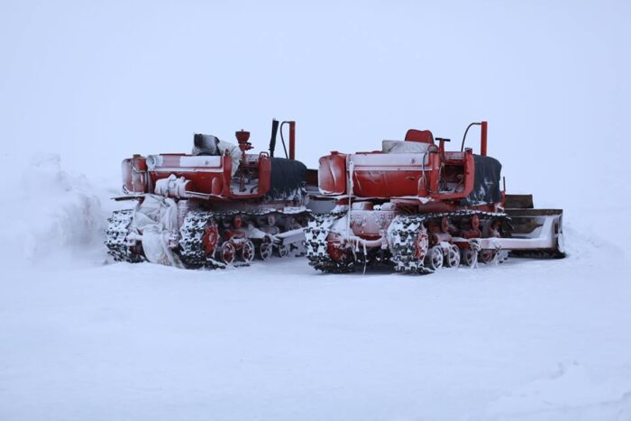Two snow tractors sit on the Arctic ocean ready to prepare an ice runway