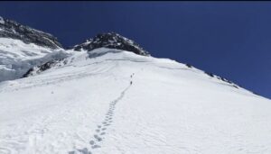 Climbers on a snow slope, a broke snow slab in front of them.