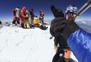 Bargiel shakes hands with the photographer on the summit of Nanga parbat, a group of skiers in background.