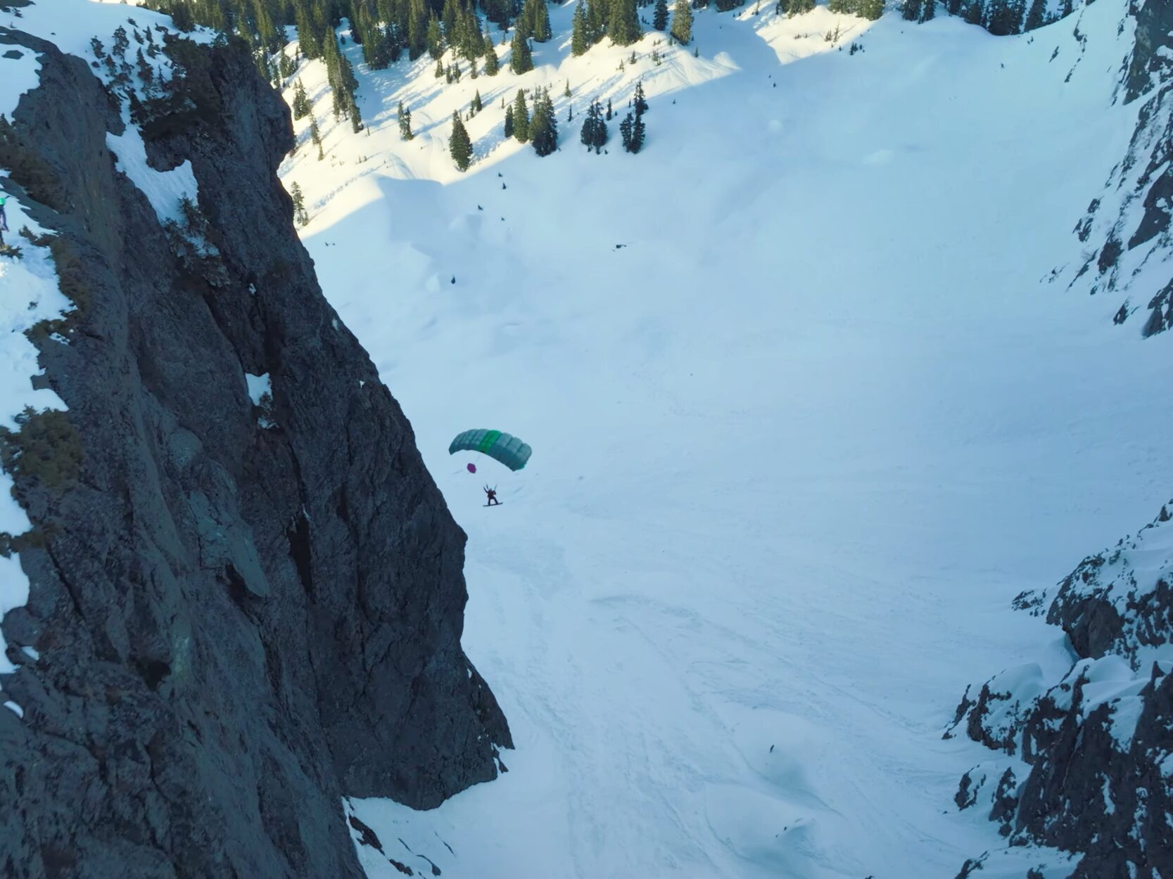 A person parachuting over snow-covered slopes