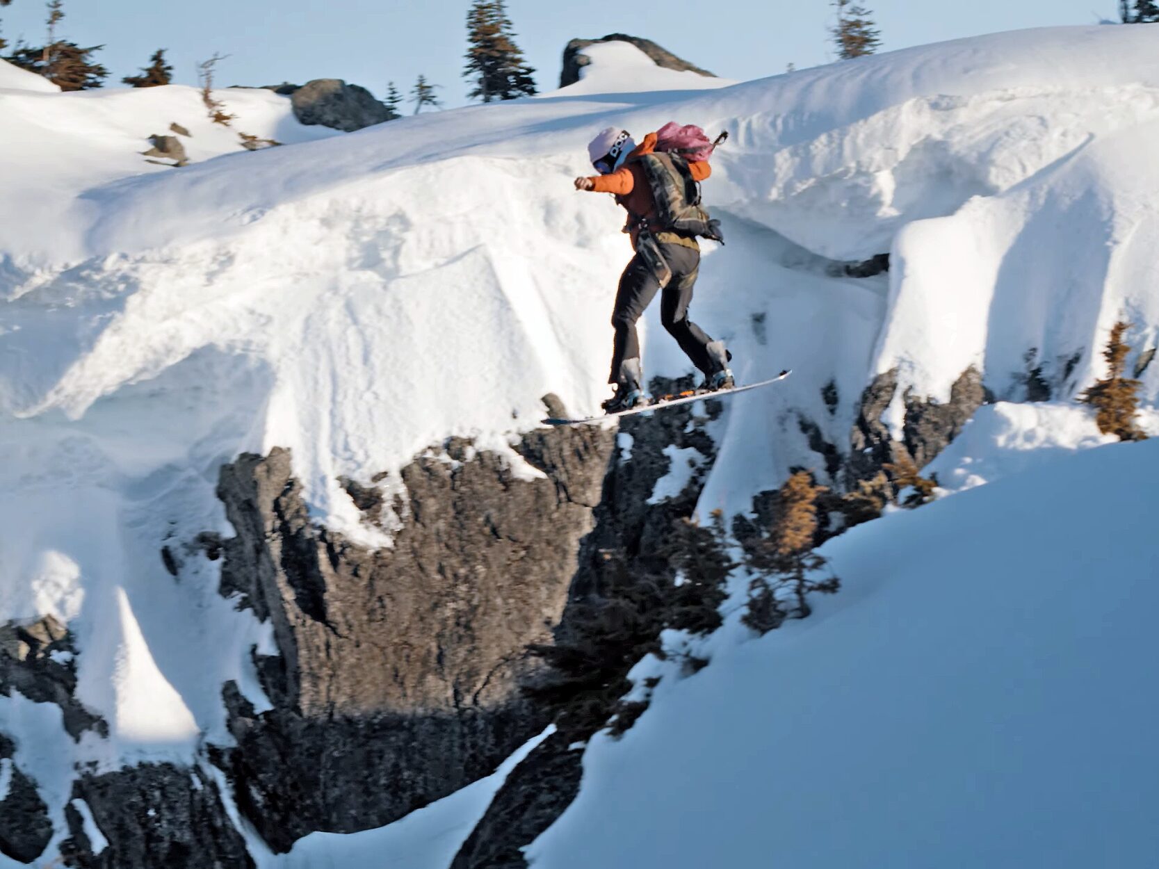A person snowboarding off of a cliff