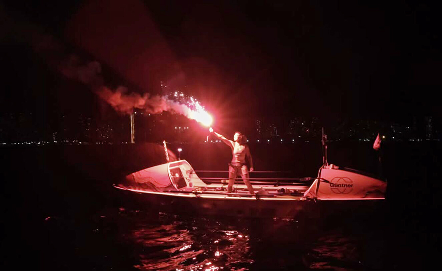 Kelsey Pfendler crosses the finish line. She stands on the boat flare in hand