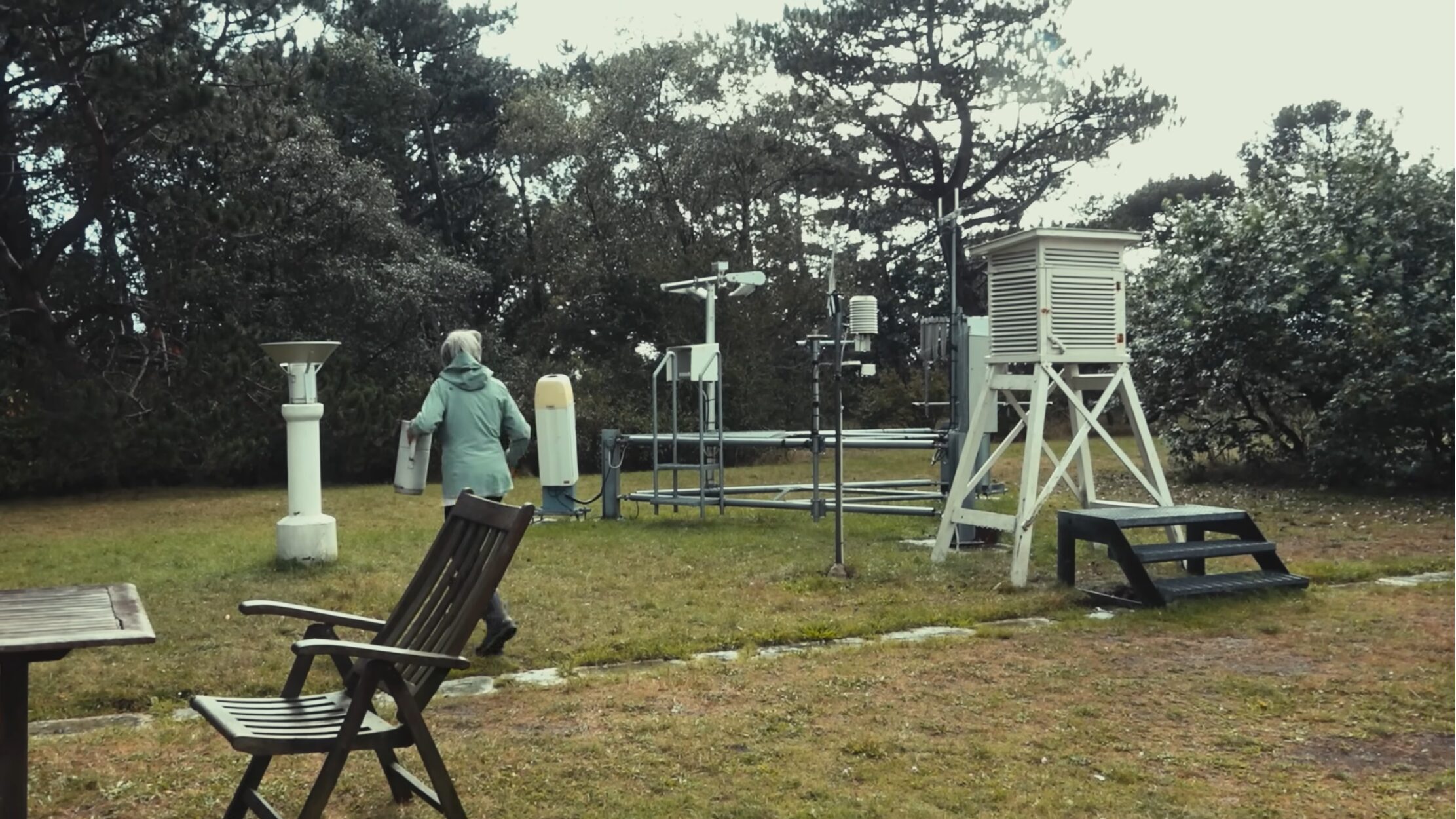 A woman walking around a weather observation setup outdoors
