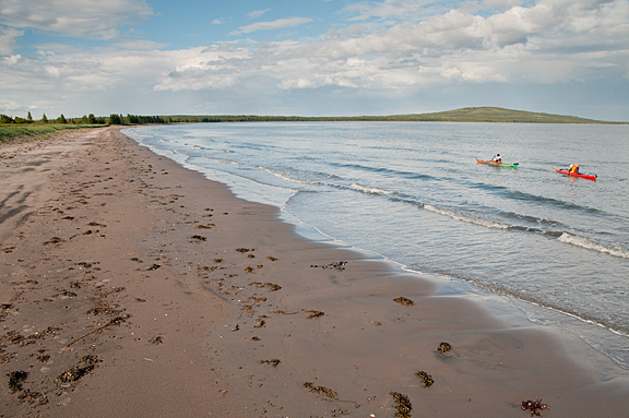 two kayakers off sand beach