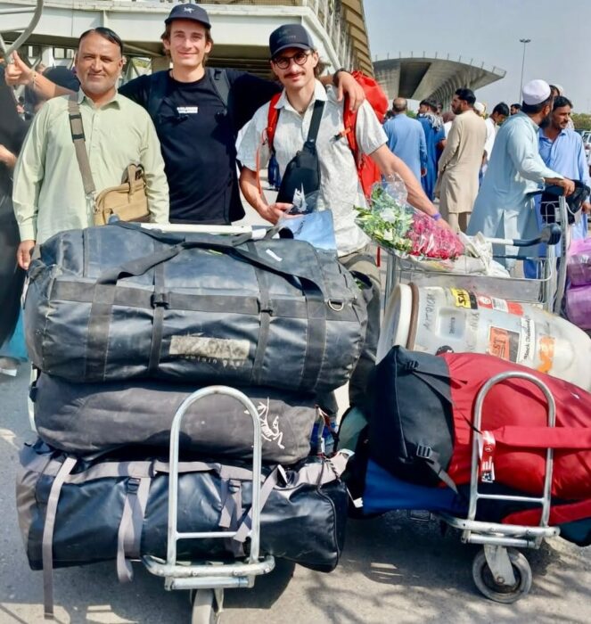Climbers in front of an airport with duffel bags and a Paklistani operator with them.