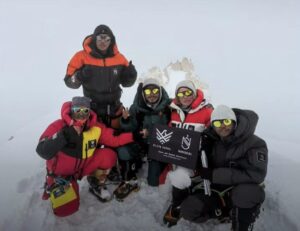 Climbers on a spiky, snowy summit in a foggy day.