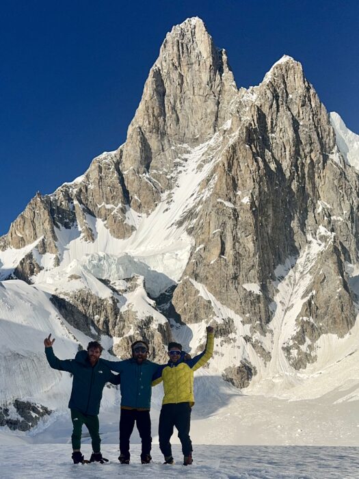 Three climbers on a snowy plateau with the impressive west face of Tahu Rutum bwhind.