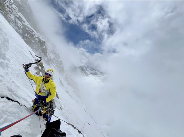 A blimber on a snowy ramp among clouds.