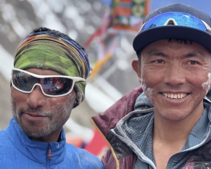 Close shot of two climbers at a puja ceremony in a Base Camp, with rice powder on their cheeks.