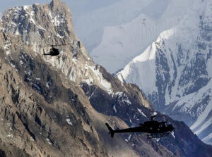 Two helicopters among big mountains.