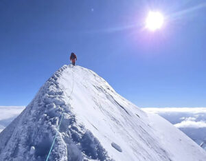 A climber on the top of a snowy ridge.