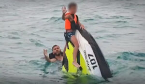 People clinging to a jet ski