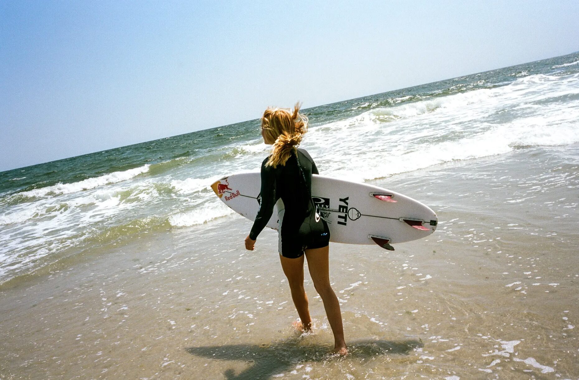Caitlin Simmers carries her surfboard towards the waves.