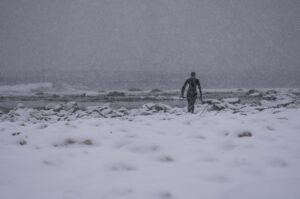 A surfer carries their surfboard across the snow in Norway. Photo: Lisa Paarvio