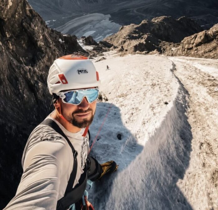a climber on a hard snow ramp, his climbing partner following in the distance. 