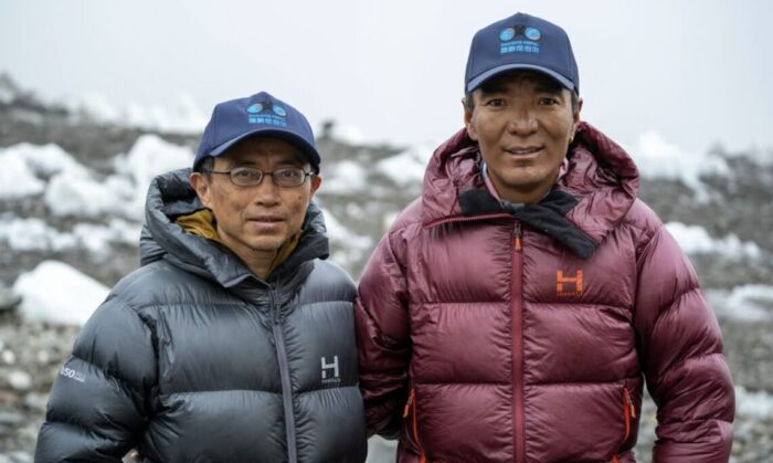Two climbers in dawn jackets at a base camp in a cloudy day.