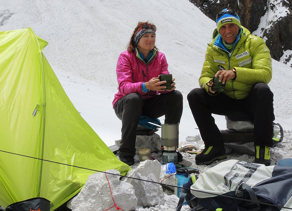 man and woman sitting in snow outside tent