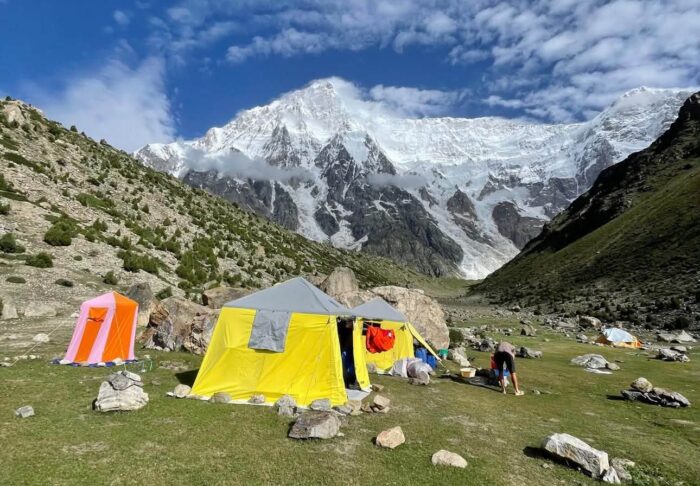 A tent on a green plain with Nanga parbat in background.