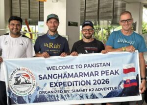Three clibers and their local operator at an airport, holding an expedition banner.