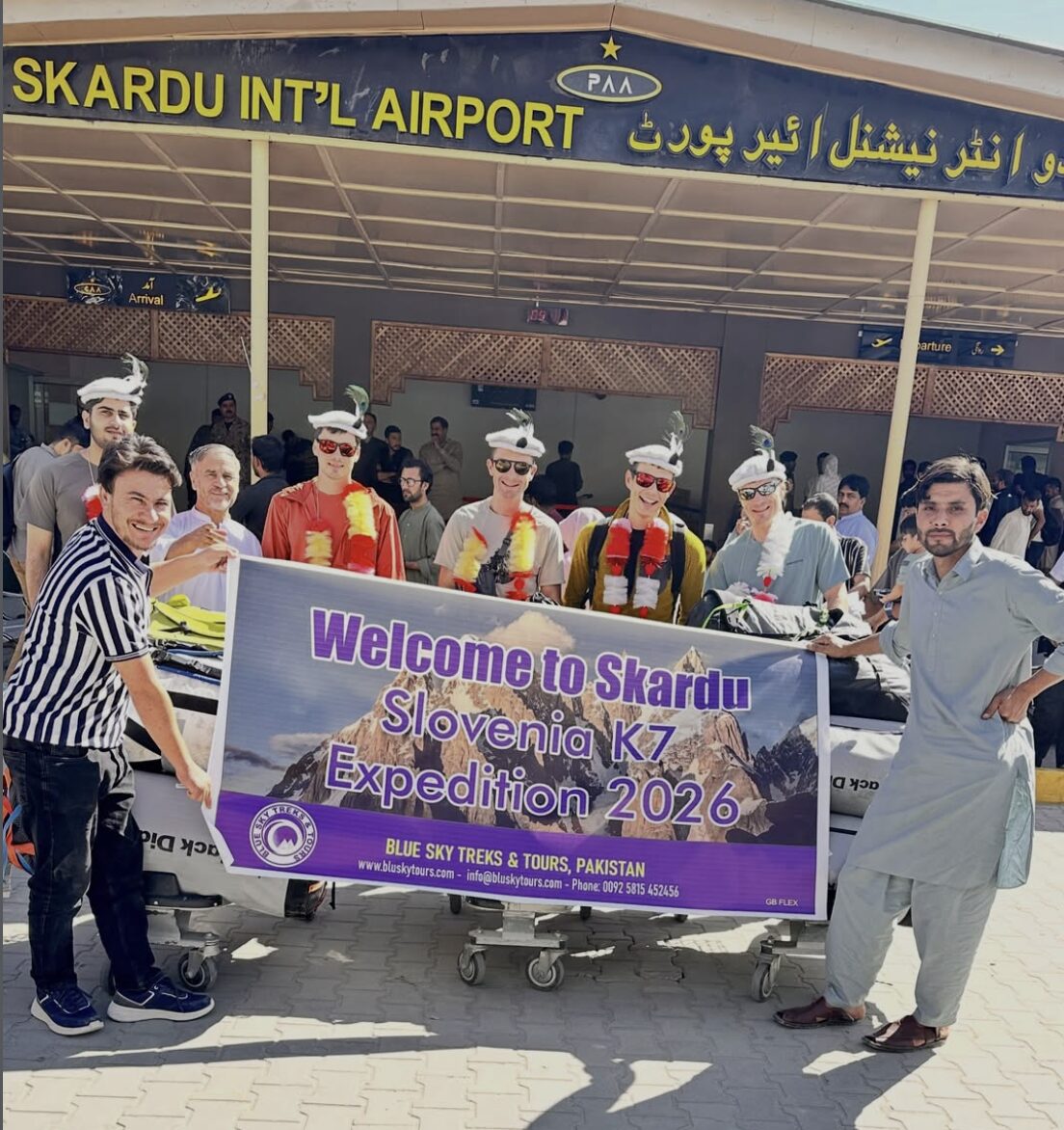 Climbers and local tour operators behind an expedition banner at the gate of Skardu Airport, Pakistan.