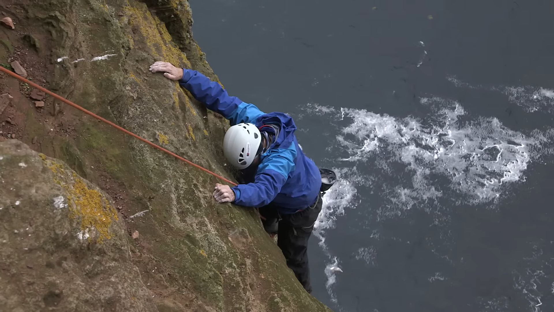 A man climbing with ocean below